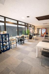a large room with tables and chairs and windows at 心斎橋難波関空直通Nambaminami direct to Shinsaibashi Ambers Hostel in Osaka