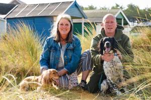 a man and a woman sitting next to two dogs at Rosie's Rest in Hunstanton