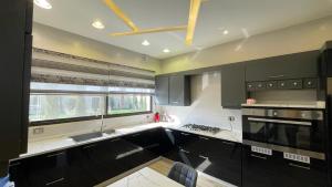 a kitchen with black cabinets and a large window at Villa W2 in Amman