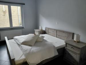 a bedroom with a white bed and a window at App ZeeVorm Nieuw in De Panne