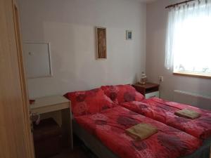 a bedroom with a red bed and a window at Bungalov Mikulášovice in Mikulášovice