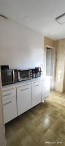 a kitchen with white cabinets and a microwave at Nossa casa in Petrópolis