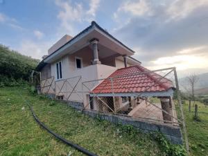 a house on a hill with a fence around it at Honey Bee Cottages in Ooty