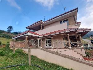 a house with a fence in front of it at Honey Bee Cottages in Ooty