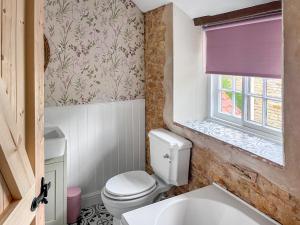 a bathroom with a toilet and a window at Teddy's Cottage in Market Overton