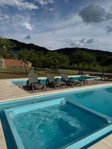 a swimming pool with chairs and a table next to it at Treffen Cabañas in Villa General Belgrano