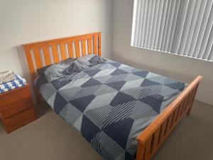 a bedroom with a bed with a blue and white comforter at Beach House Shared in Alkimos