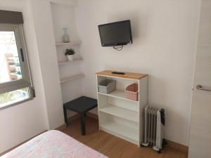 a bedroom with a tv on the wall and a desk at Apartamentos Guillem in Playa de Miramar