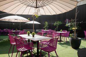a patio with purple chairs and tables with umbrellas at The PopCity Hotel in Santiago