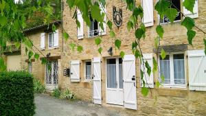 an old stone building with white doors and windows at Au Pied du CHÂTEAU - 5 à 11 personnes - Baignade-canoë-piste cyclable à 100 m in Castelnaud La Chapelle