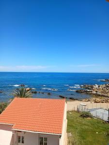 a house with an orange roof next to the ocean at Appart hôtel palais de mer in Jijel