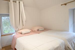 two beds sitting next to a window in a bedroom at Au petit jardin d'Aizenay in Aizenay