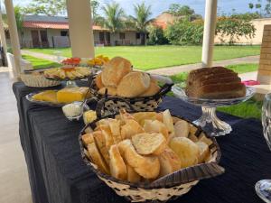 a table topped with baskets of bread and cakes at Pousada Elizium in Montes Claros