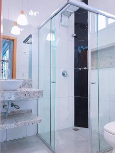 a bathroom with a glass shower and a sink at suite ampla em sobrado com ar e garagem in Cascavel