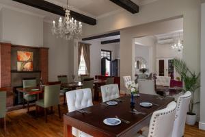 a dining room with a table and white chairs at Wild Mushroom Country House in Stellenbosch