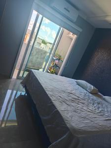 a bedroom with a bed and a large window at suite ampla em sobrado com ar e garagem in Cascavel