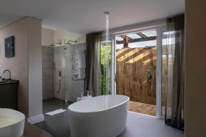 a bathroom with a white tub and a shower at Wild Mushroom Country House in Stellenbosch +60 photos