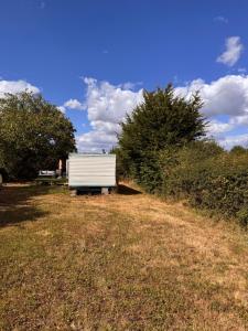 a white trailer sitting in the middle of a field at Le joli centre energetique in Châteaumeillant