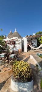 a patio with two benches and flowers in front of a building at Trulli di Ivana in Ostuni