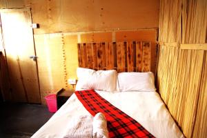 a bedroom with a bed with a plaid blanket on it at Mambo Game View in Elmenteita