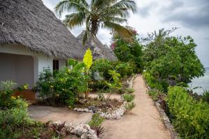 a path leading to a house with a thatch roof at VeriDiana Hotel Zanzibar in Dimbani