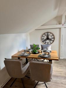 ein Esstisch mit Stühlen und eine Uhr an der Wand in der Unterkunft Apartment Oberdeck für 4 Personen, Wifi, Parkplätze uvm in Brokstedt