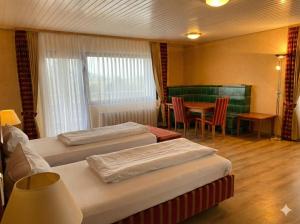 a hotel room with two beds and a table and a dining room at Hotel Hebelhof in Bad Bellingen