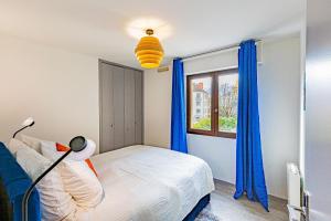 a bedroom with a bed and a window with blue curtains at Le 28 C chouette - Spacieux - Box privé - Ascenseur - Centre in Dijon