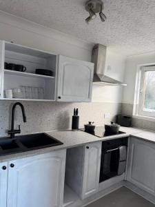 a kitchen with white cabinets and a sink at Nessy5 Apartment in Inverness