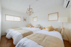 three beds in a room with white walls and windows at Aso Vista in Aso