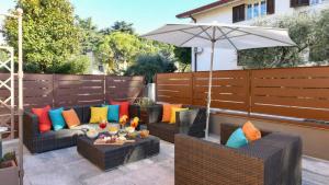 a patio with two couches and an umbrella at Villa Bugatti Indipendent Villa ,lake view and private pool, DesenzanoLoft Official Partner Homes & Villas by Marriott Bonvoy in Desenzano del Garda +49 photos