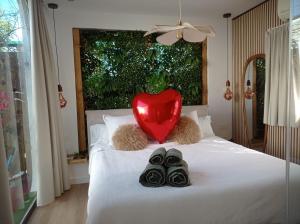 a heart sitting on top of a bed with shoes at Casita acristalada con jacuzzi in Tiñosa Alta