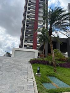 a tall building with a palm tree in front of it at Ap Studio Premium luxuoso novíssimo! in Sorocaba