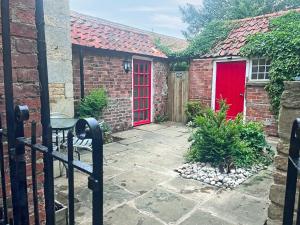 a red door on a brick house with a patio at Teddy's Cottage in Market Overton