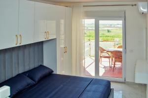 a bedroom with a bed and a balcony with a table at Flat in Shëngjin Beachfront Getaway in Shëngjin