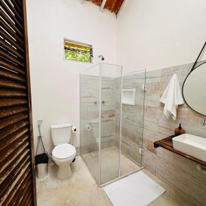 a bathroom with a toilet and a glass shower at Refugio Ilha Grande in Angra dos Reis