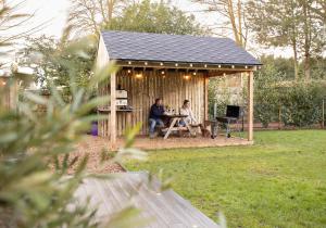 two people sitting in a gazebo in a yard at City to Country Retreat Luxury Lodges with Hot Tub, BBQ, Fire Pit in Toppesfield