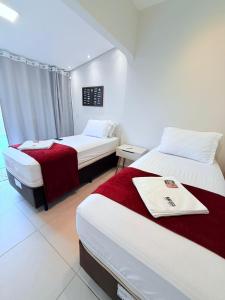 a hotel room with two beds with red and white sheets at NAVEGA HOSTEL - Rede Navega Hotéis in Navegantes