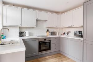 a white kitchen with white cabinets and appliances at Edward Cottage - Old Town Poole Home, Moments from Poole Quay in Poole