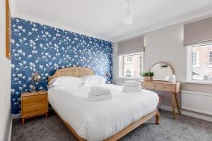 a bedroom with a large bed with a blue wall at Edward Cottage - Old Town Poole Home, Moments from Poole Quay in Poole