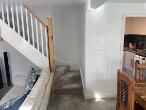 a living room with a staircase and a couch at Ty capel cottage in Mold