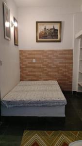 a bed in a room with a brick wall at Condomínio Vila Gustavo excelente localização in Caraguatatuba