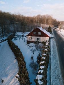 a house with snow on the ground next to a road at Domek pod lasem in Kańczuga