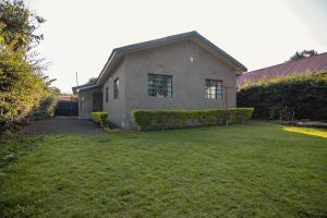 a house with a grass yard in front of it at Open Gate House in Arusha