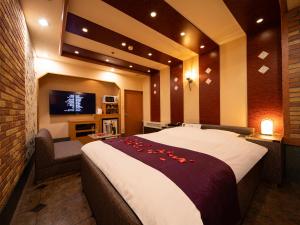 a bedroom with a large bed and a tv at Hotel Metro (Adult Only) in Yokohama