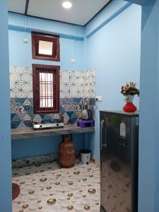a kitchen with blue walls and a refrigerator at DENEVA Inn in Nowgong