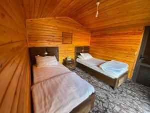two beds in a room with wooden walls at Naif Bedouin tour in Wadi Rum