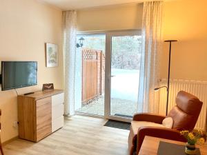 a living room with a tv and a chair and a sliding glass door at Kleine Oase 46 in Funfseen