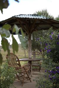 a table and two chairs under a wooden umbrella at Mambo Game View in Elmenteita