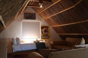a bedroom with a bed and a couch and a window at Die Nagmaalhuisie in Montagu